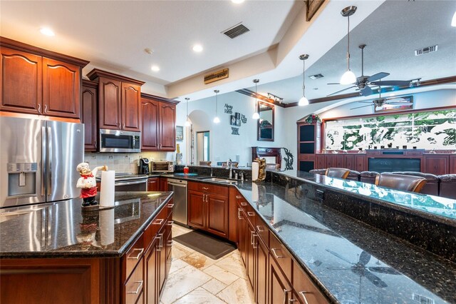 kitchen featuring decorative light fixtures, kitchen peninsula, sink, ceiling fan, and appliances with stainless steel finishes