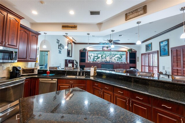 kitchen with ornamental molding, appliances with stainless steel finishes, ceiling fan, and hanging light fixtures