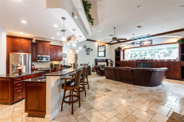 kitchen featuring a kitchen island, a breakfast bar area, pendant lighting, stainless steel appliances, and ceiling fan