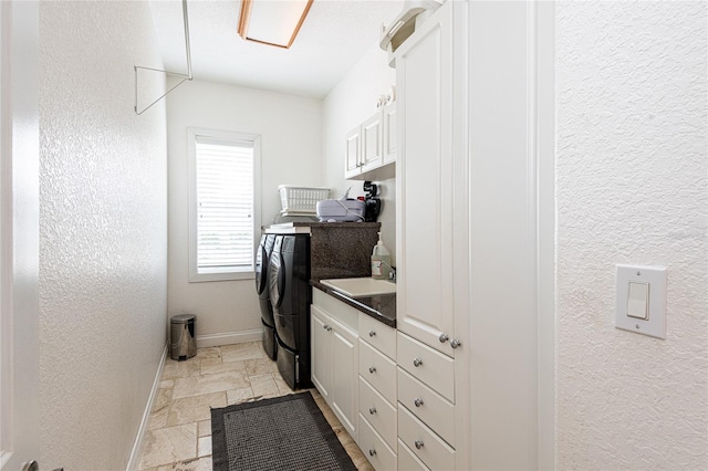 laundry room with washing machine and clothes dryer, cabinets, and sink