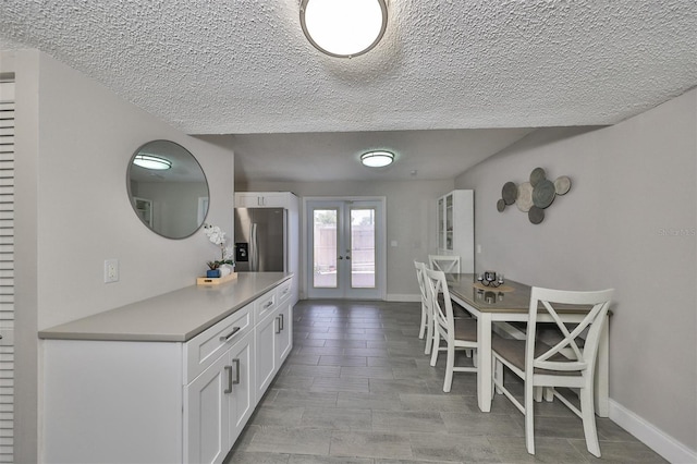 kitchen featuring stainless steel fridge, a textured ceiling, french doors, and white cabinets