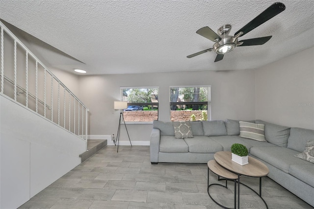 living room featuring ceiling fan and a textured ceiling