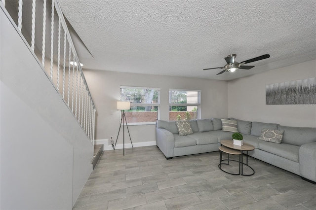 living room featuring light wood-type flooring, a textured ceiling, and ceiling fan