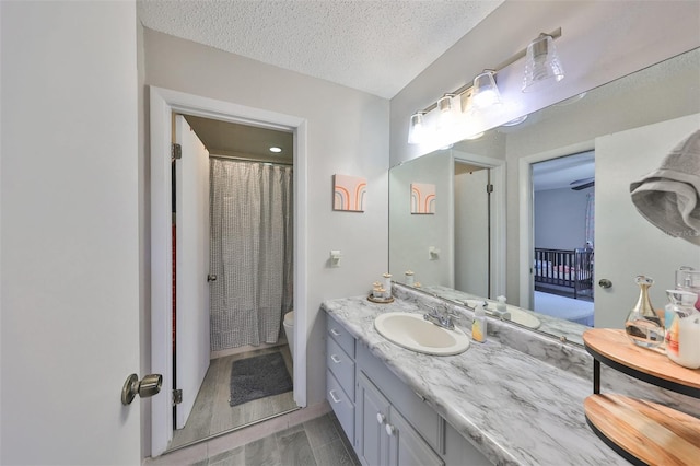 bathroom with a textured ceiling, vanity, toilet, and hardwood / wood-style flooring