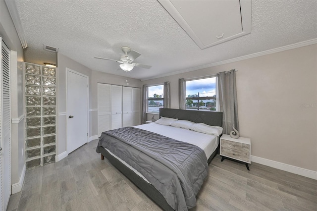 bedroom with a textured ceiling, light hardwood / wood-style flooring, and ceiling fan