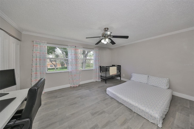 bedroom with ornamental molding, a textured ceiling, wood-type flooring, ceiling fan, and a closet