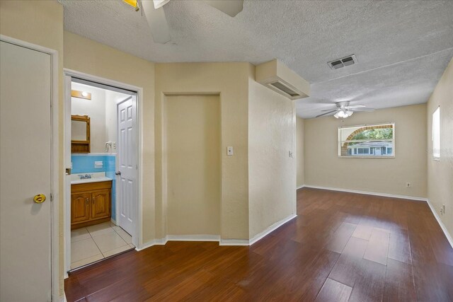 unfurnished room with a textured ceiling, hardwood / wood-style flooring, ceiling fan, and sink