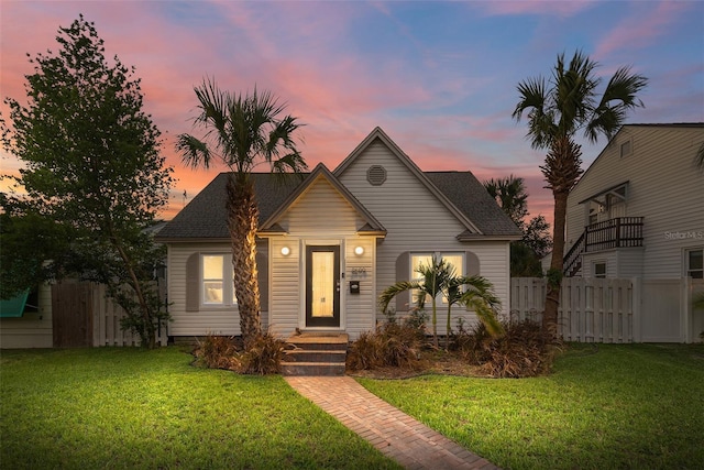 bungalow-style home featuring fence and a lawn