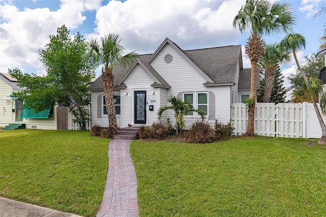 view of front of home featuring roof with shingles, a front yard, and fence