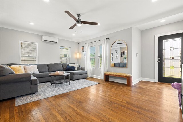 living room with ceiling fan, a wall unit AC, and hardwood / wood-style flooring