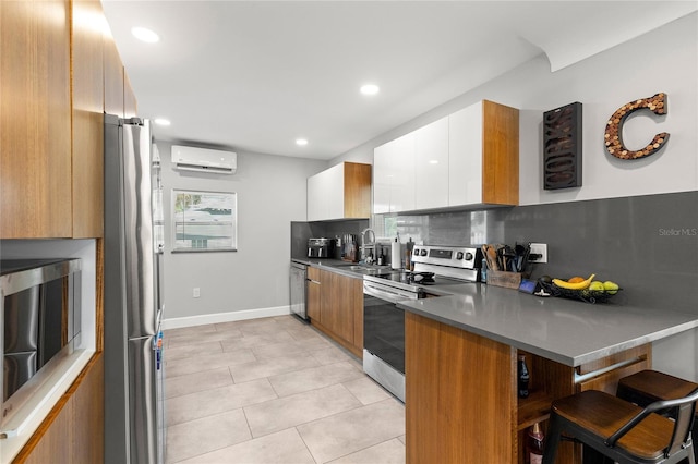 kitchen with modern cabinets, appliances with stainless steel finishes, a kitchen breakfast bar, a peninsula, and a sink