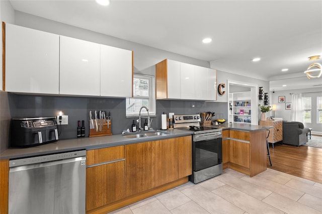 kitchen with light wood-type flooring, stainless steel appliances, white cabinetry, sink, and decorative backsplash