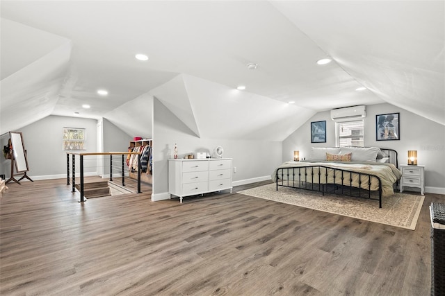 bedroom with multiple windows, a wall unit AC, and wood finished floors