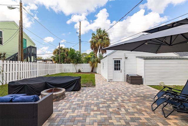 view of patio featuring a fenced backyard, a fire pit, and an outdoor structure