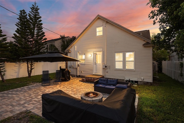 back house at dusk featuring an outdoor living space with a fire pit, a lawn, and a patio