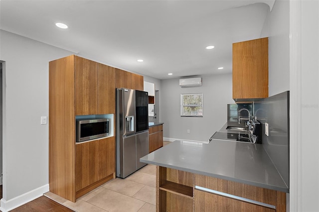 kitchen featuring brown cabinets, stainless steel appliances, a sink, modern cabinets, and a wall mounted air conditioner