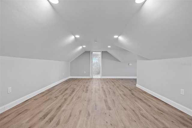 additional living space with vaulted ceiling, light wood-style flooring, and baseboards