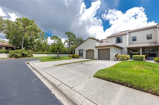 view of front of property featuring concrete driveway, fence, an attached garage, and stucco siding