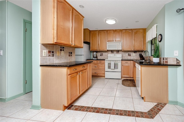 kitchen featuring white appliances, light tile patterned floors, backsplash, and a sink