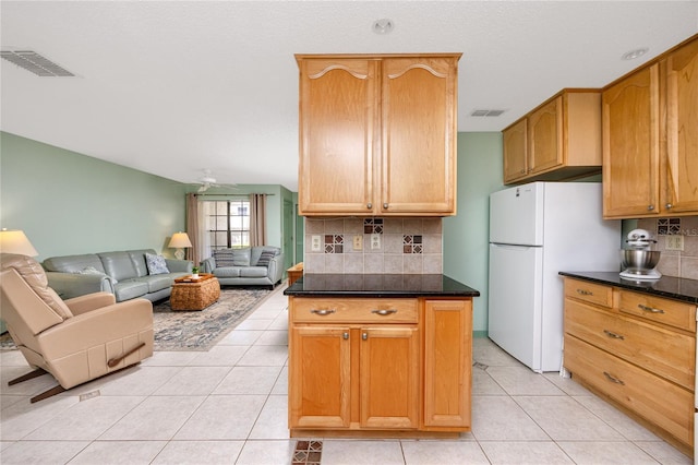 kitchen featuring dark countertops, freestanding refrigerator, light tile patterned flooring, and visible vents