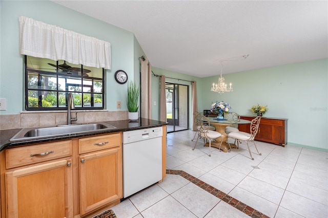 kitchen featuring light tile patterned floors, a notable chandelier, a sink, dishwasher, and dark countertops