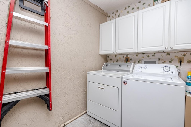 clothes washing area with a textured wall, separate washer and dryer, and cabinet space