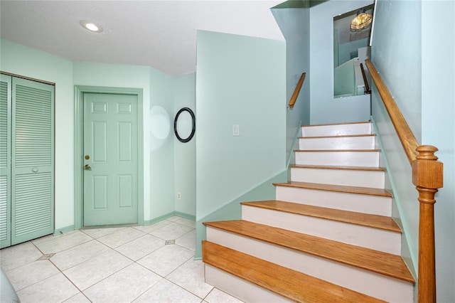 staircase featuring a textured ceiling, recessed lighting, tile patterned flooring, and baseboards