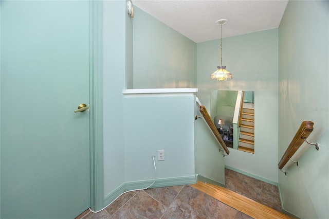 staircase featuring a textured ceiling and baseboards