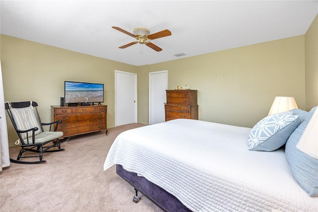 carpeted bedroom featuring a textured ceiling, visible vents, and a ceiling fan