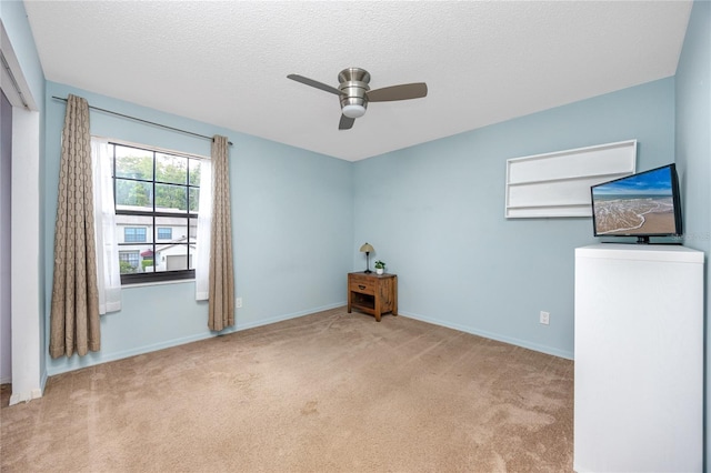 empty room featuring carpet flooring, ceiling fan, a textured ceiling, and baseboards