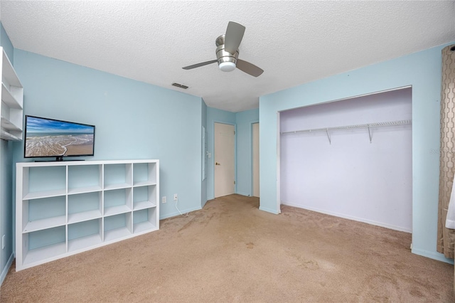 unfurnished bedroom featuring carpet, a closet, visible vents, ceiling fan, and a textured ceiling