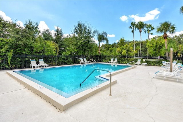 pool with a patio area and fence