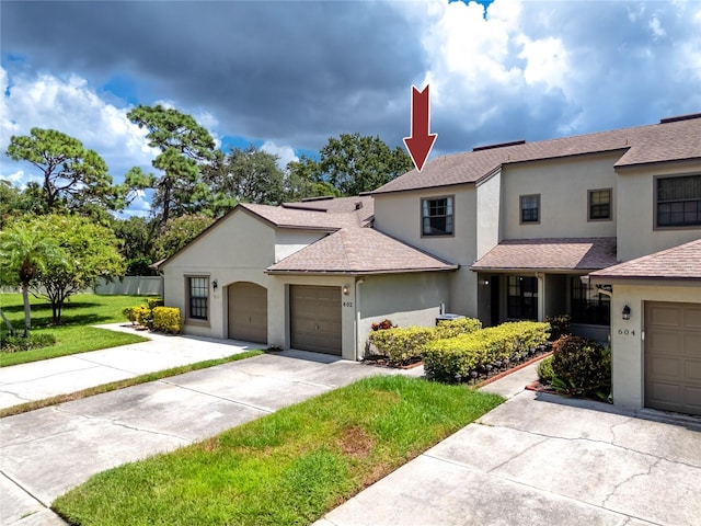 view of front of home featuring stucco siding, a shingled roof, an attached garage, a front yard, and driveway