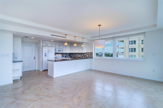 kitchen featuring white appliances, pendant lighting, backsplash, kitchen peninsula, and white cabinetry