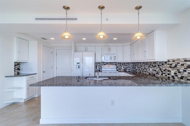 kitchen with hanging light fixtures, dark stone counters, white appliances, and white cabinets