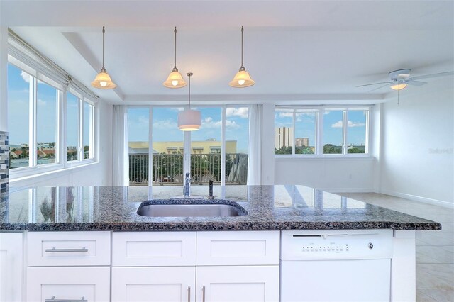 kitchen with white dishwasher, pendant lighting, dark stone countertops, ceiling fan, and white cabinets