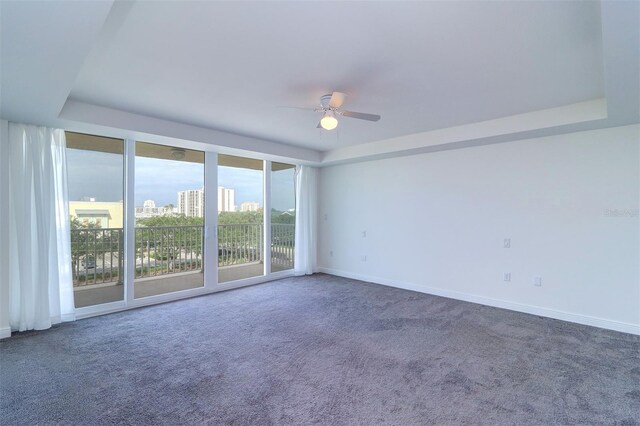 carpeted empty room with a raised ceiling and ceiling fan