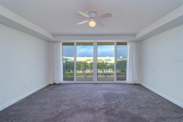 empty room featuring ceiling fan, dark colored carpet, and a healthy amount of sunlight