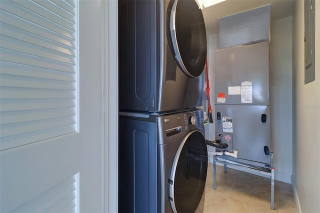 laundry room with light tile patterned floors, electric panel, stacked washer / dryer, and heating unit