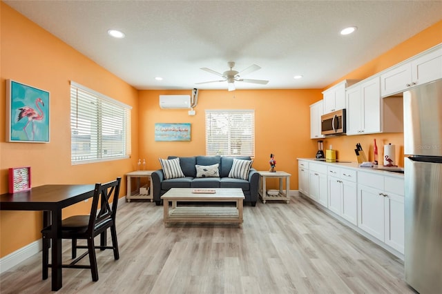 living room featuring light wood-type flooring, a wall mounted air conditioner, plenty of natural light, and ceiling fan