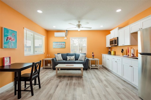 living room with light wood finished floors, plenty of natural light, baseboards, and a wall mounted air conditioner