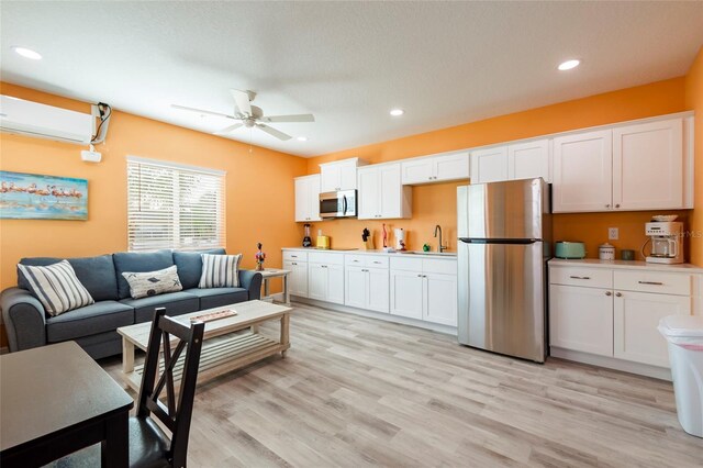 living room featuring ceiling fan, sink, a wall mounted air conditioner, and light hardwood / wood-style flooring