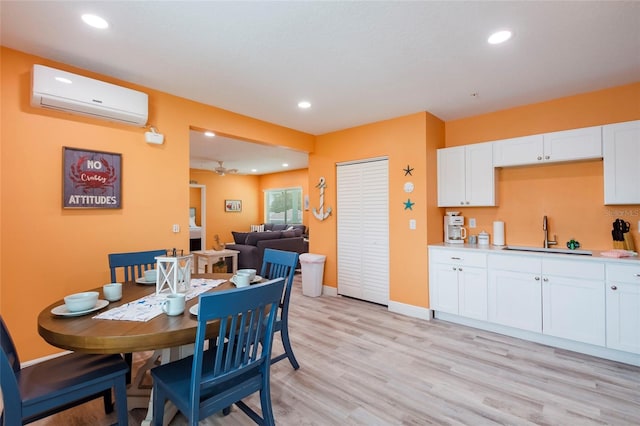 dining space featuring sink, light hardwood / wood-style flooring, and a wall unit AC