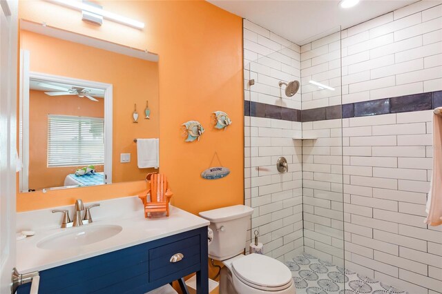 bathroom with tiled shower, toilet, ceiling fan, and vanity