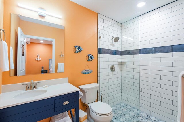 bathroom featuring toilet, a tile shower, and vanity