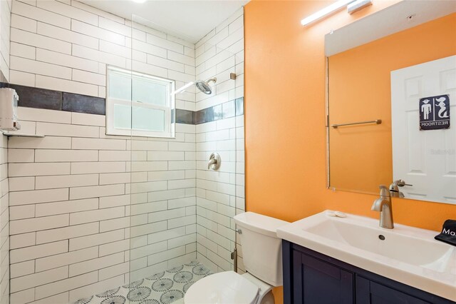 bathroom with vanity, tiled shower, and toilet