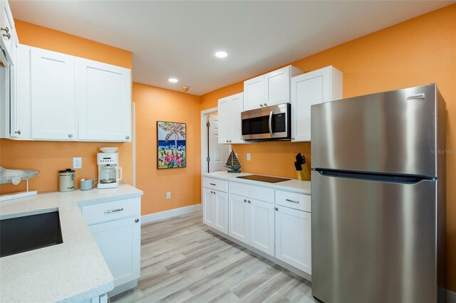 kitchen featuring stainless steel appliances, light hardwood / wood-style floors, white cabinets, and light stone counters