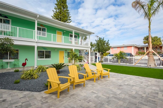 view of patio featuring fence and a balcony