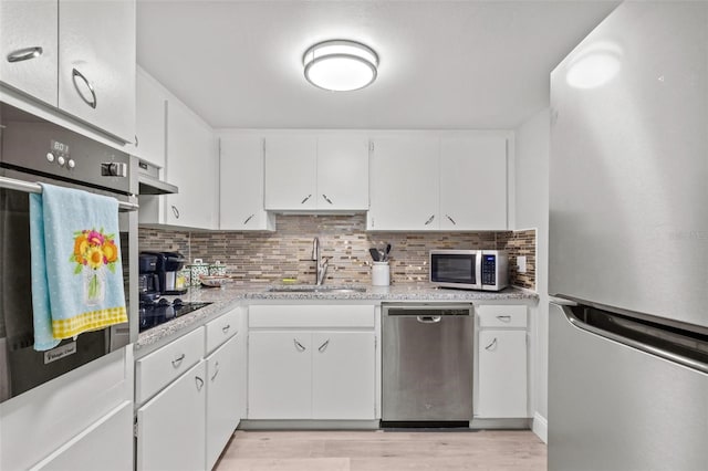 kitchen with sink, white cabinets, light wood-type flooring, and stainless steel appliances