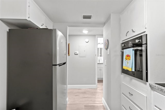 kitchen featuring light hardwood / wood-style floors, electric panel, stainless steel appliances, and white cabinets